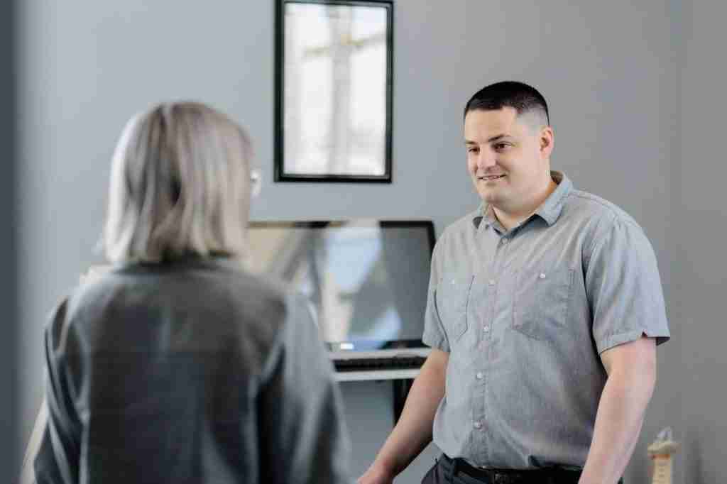 A man and woman standing together in front of a computer, collaborating